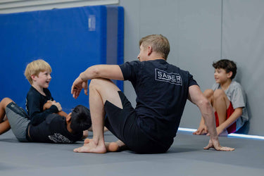 Coach in a gym setting with children on a mat